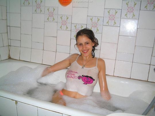 Молоденькая девушка в ярких бикини и майке принимает ванную